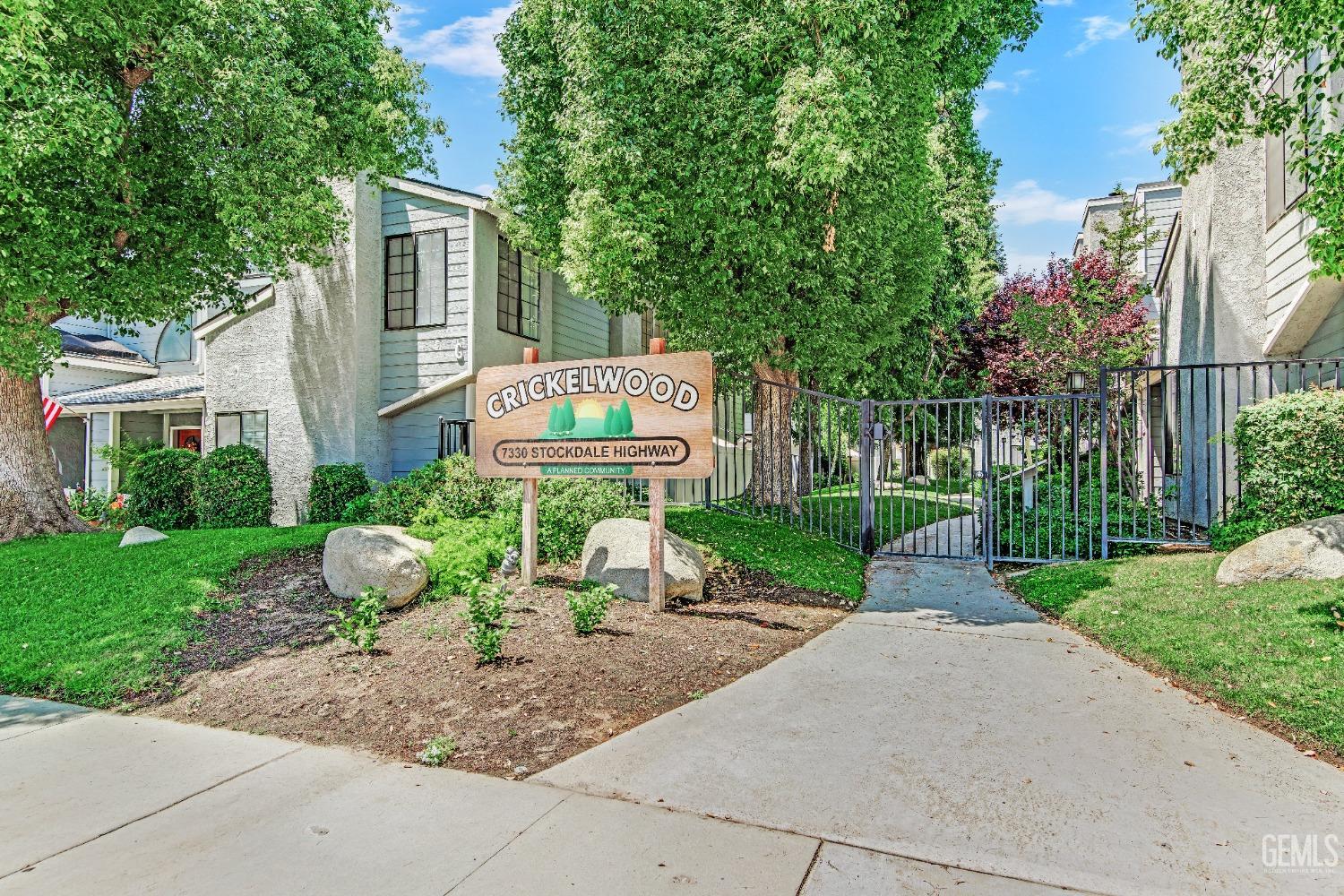 a sign board with flower plants and big trees