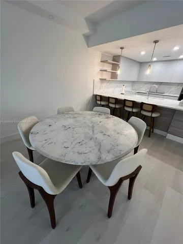 a living room with stainless steel appliances furniture a rug and a kitchen view