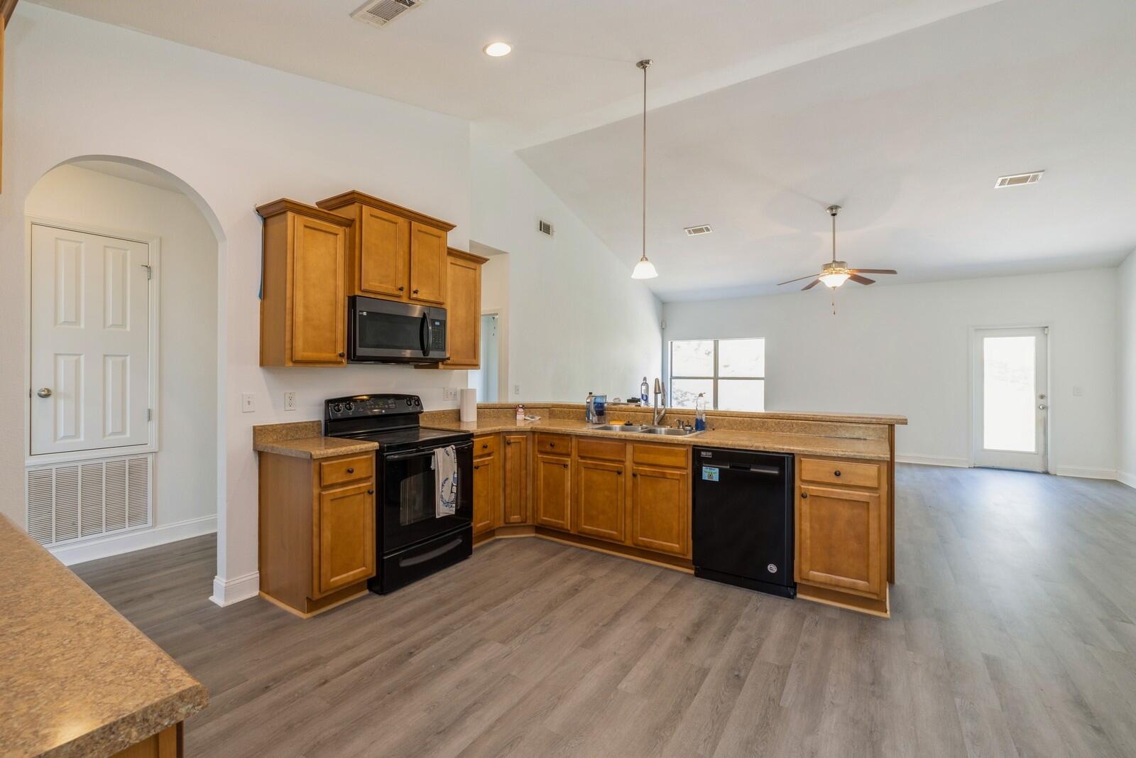 410 Wych Circle Crestview, FL 32536 - Photo 32 of 34 a kitchen with stainless steel appliances granite countertop a stove a sink dishwasher a microwave oven and a dining table with wooden floor