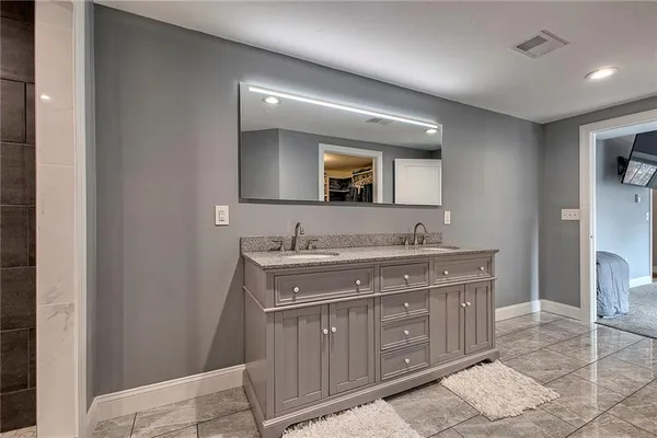 a bathroom with a granite countertop double vanity sink and mirror