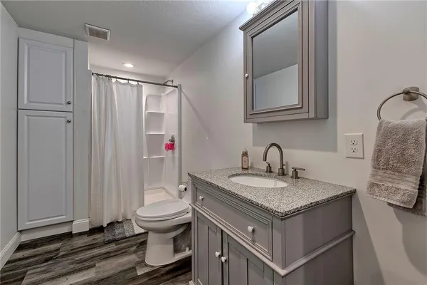 a bathroom with a granite countertop toilet sink and mirror