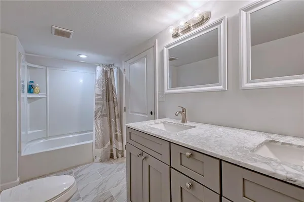 a bathroom with a granite countertop sink a toilet and shower