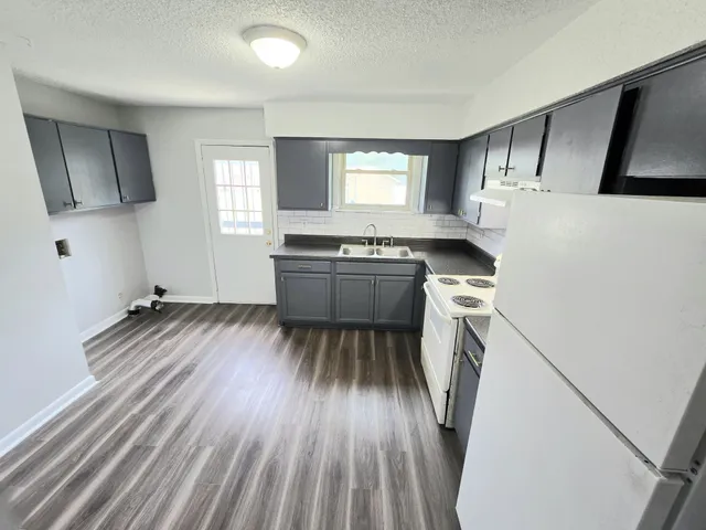 a kitchen with sink a refrigerator and wooden floor