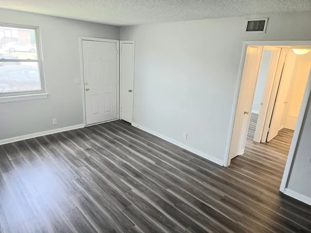 an empty room with wooden floor and windows