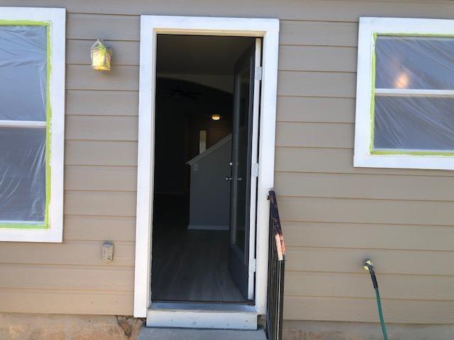 9217 Rowlands Sayle Road Austin, TX 78744 - Photo 17 of 18 A welcoming entryway features horizontal siding, white-trimmed windows, and a glass-paneled door.