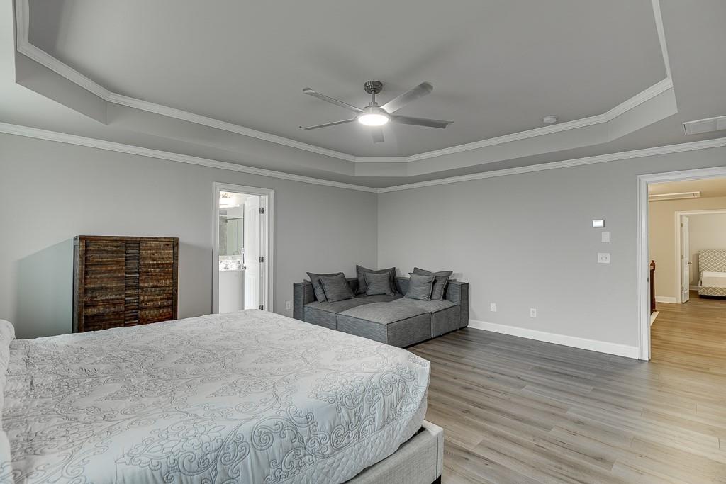 914 Rainsong Court Braselton, GA 30517 - Photo 17 of 37 a bedroom with a large bed and a chandelier