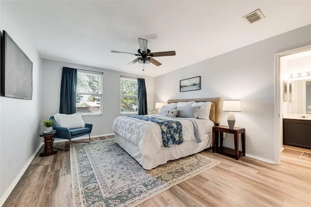 a spacious bedroom with a bed a couch and a flat tv screen on the dresser