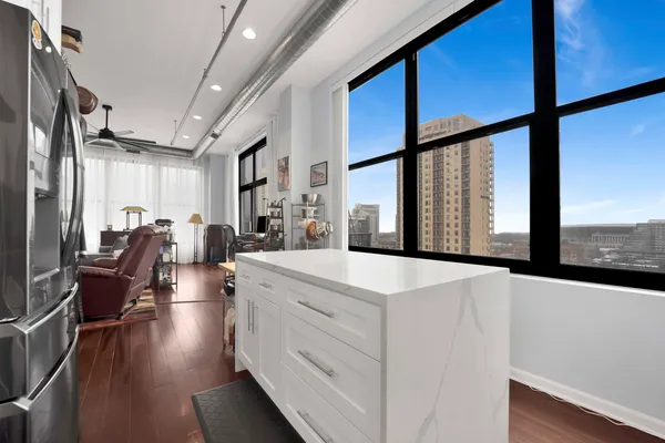 a view of a kitchen with kitchen island granite countertop a large window a sink and appliances