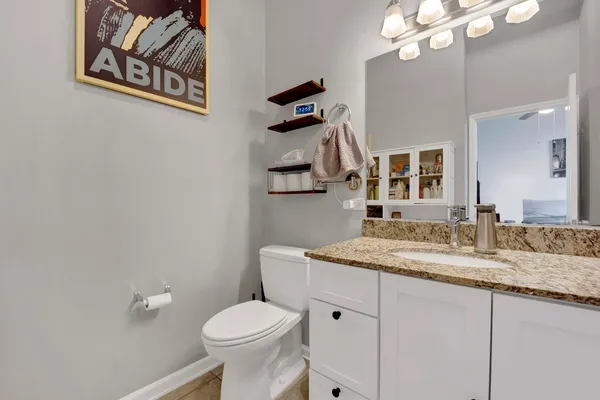 a bathroom with a granite countertop sink mirror vanity and toilet