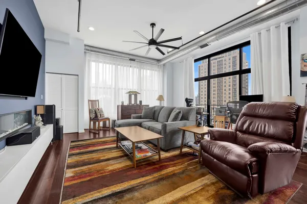 a living room with furniture a flat screen tv and a large window