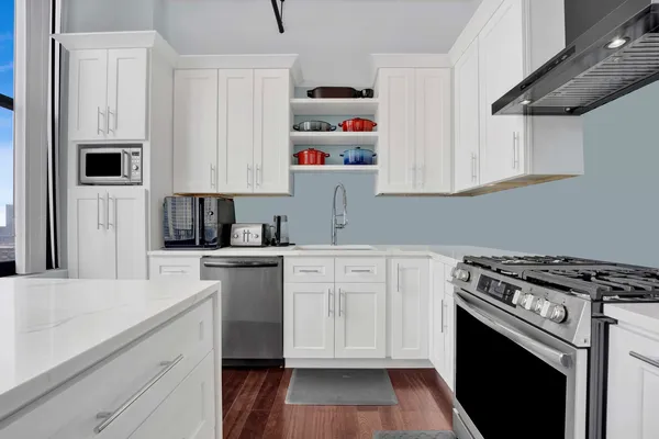 a kitchen with cabinets stainless steel appliances a sink and wooden floor