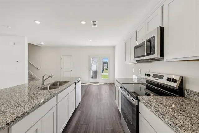 a kitchen with kitchen island granite countertop a sink stove and cabinets