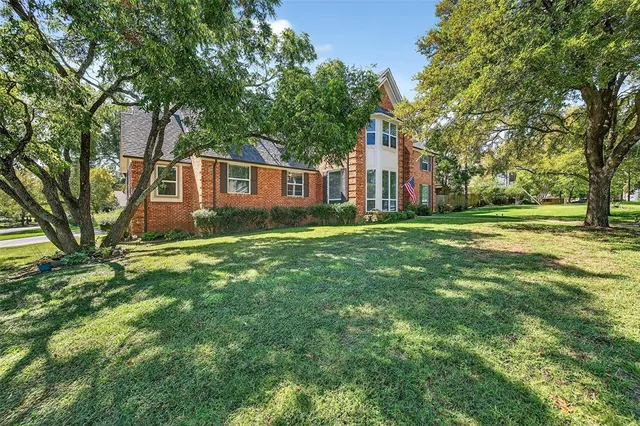 a view of a house with a big yard and large trees