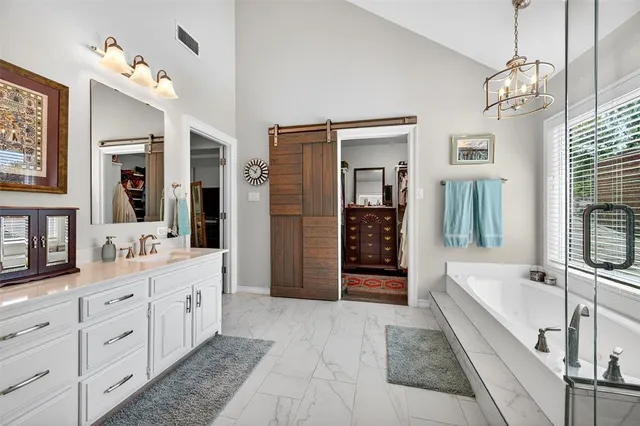 a spacious en suite bathroom with a tub double sink and mirror