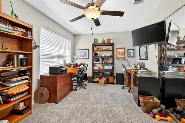 a view of a livingroom with workspace and a ceiling fan
