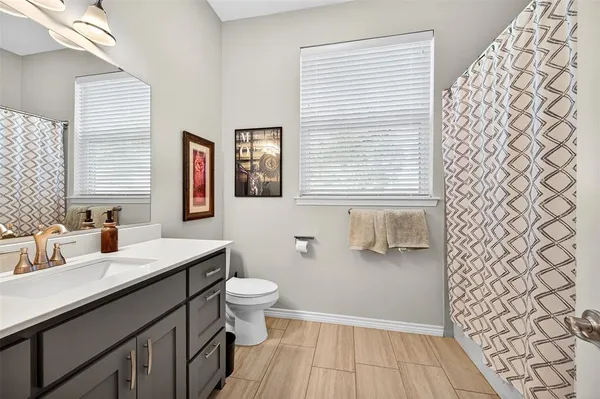 a bathroom with a sink a toilet a window and vanity