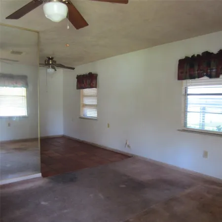 an empty room with windows and fan