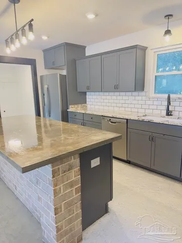 a kitchen with stainless steel appliances a sink a stove a refrigerator and cabinets