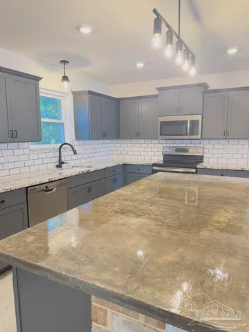 a kitchen with kitchen island a sink stainless steel appliances and counter space