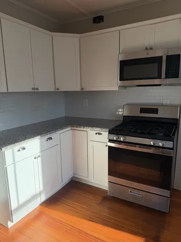 a kitchen with stainless steel appliances white cabinets and a stove top oven