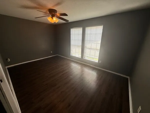 an empty room with wooden floor and windows