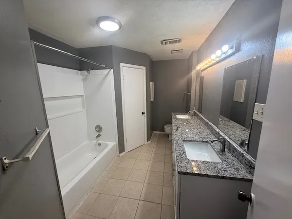 a bathroom with a granite countertop sink a toilet and shower