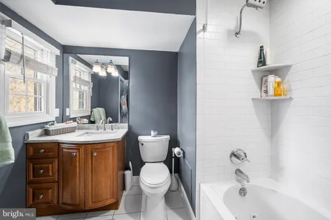 a bathroom with a granite countertop sink a toilet and bathtub