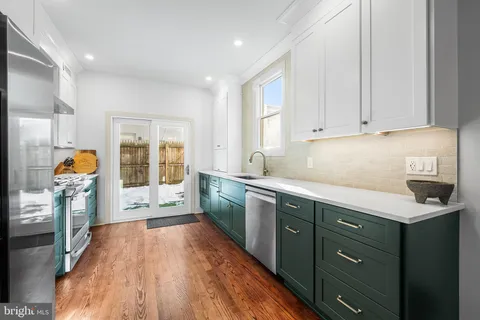 a kitchen with stainless steel appliances granite countertop a refrigerator a sink dishwasher a stove and white cabinets with wooden floor