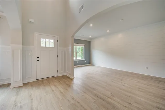 a view of an empty room with wooden floor and window