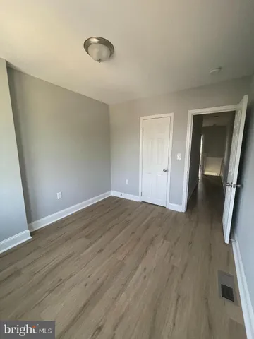 an empty room with wooden floor and mirror