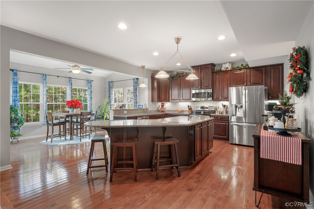 7031 Crackerberry Drive Moseley, VA 23120 - Photo 4 of 47 a kitchen with stainless steel appliances granite countertop a stove top oven a refrigerator a dining table and chairs with wooden floor