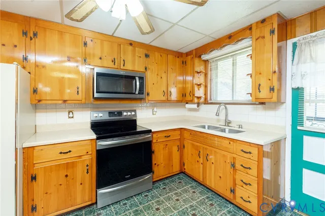 a kitchen with stainless steel appliances granite countertop a sink a stove and a wooden cabinets