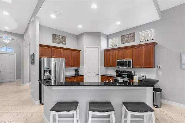 a kitchen with stainless steel appliances a refrigerator a stove a sink a dining table and chairs cabinets