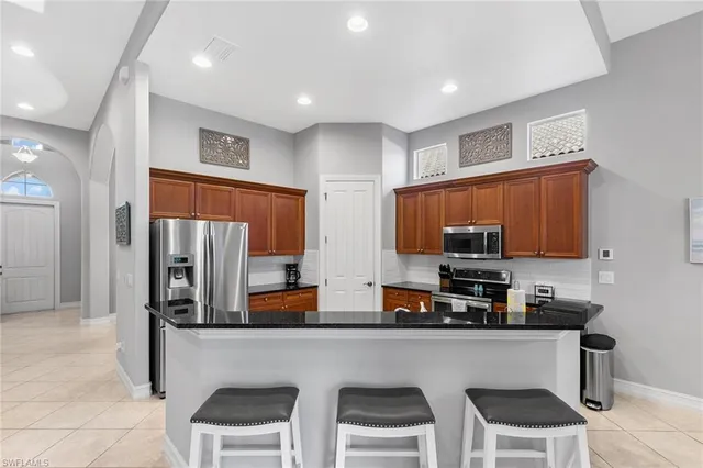 a kitchen with stainless steel appliances a refrigerator a stove a sink a dining table and chairs cabinets