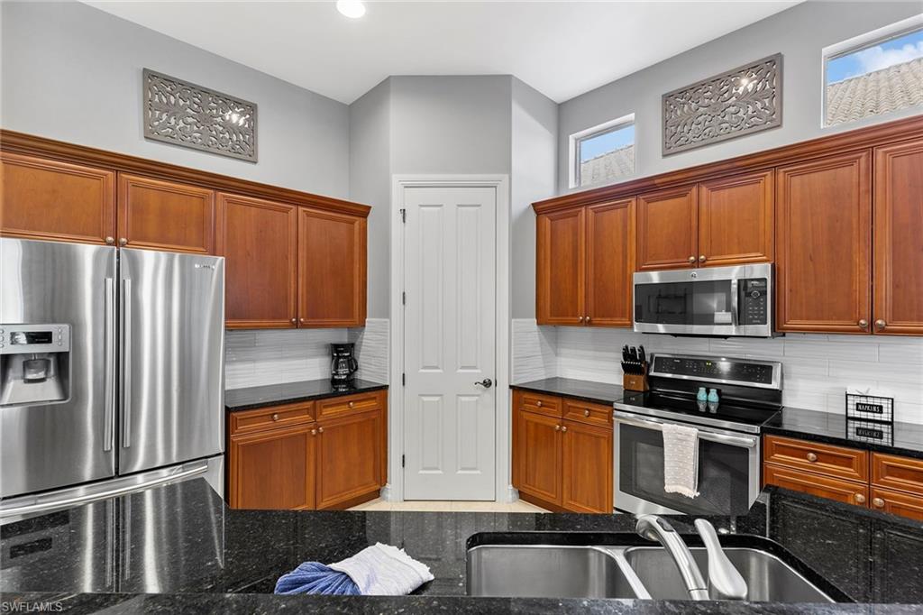 7778 Ashton Road Naples, FL 34113 - Photo 9 of 26 a kitchen with stainless steel appliances a stove a sink and a refrigerator