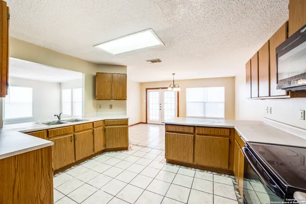 a large kitchen with granite countertop lots of white cabinets a sink and dishwasher