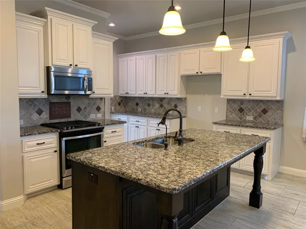 a kitchen with stainless steel appliances granite countertop a stove refrigerator and microwave