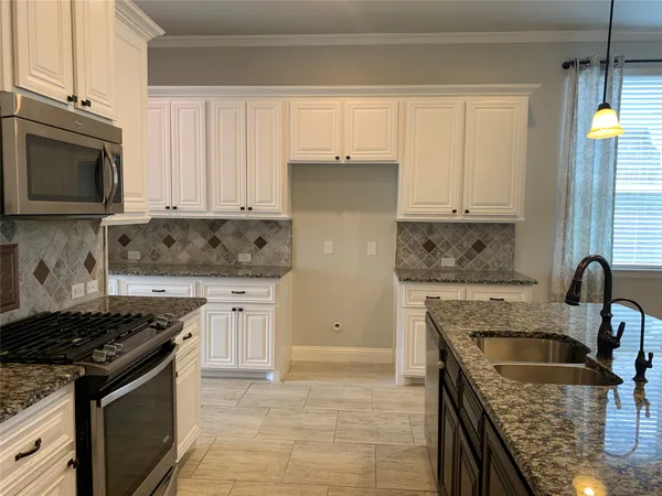 a kitchen with granite countertop a stove sink and cabinets