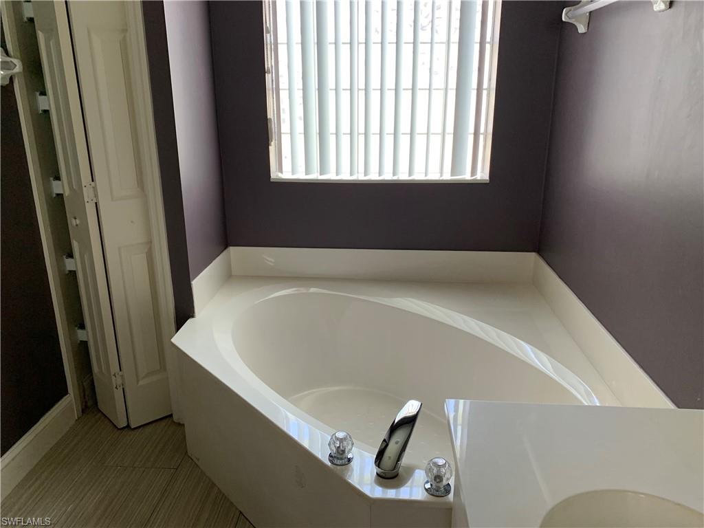 697 Crossfield Circle Naples, FL 34104 - Photo 11 of 12 a bath tub sitting in a bathroom next to a window