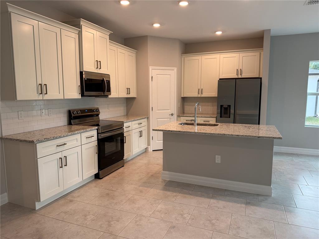1569 Kerman Street North Port, FL 34288 - Photo 3 of 26 a kitchen with kitchen island granite countertop a sink counter top space stainless steel appliances and cabinets