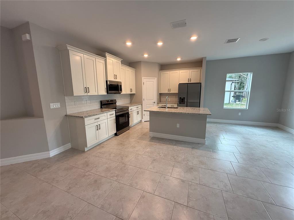 1569 Kerman Street North Port, FL 34288 - Photo 4 of 26 a kitchen with kitchen island granite countertop a stove sink and cabinets