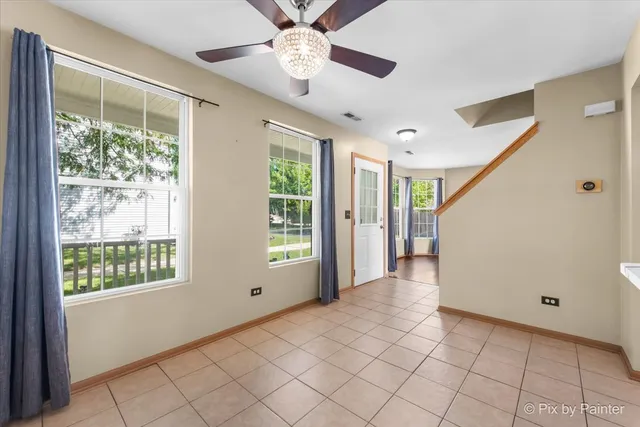 a view of an empty room with window and chandelier fan
