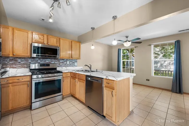 a kitchen with stainless steel appliances granite countertop a stove top oven a sink dishwasher and a refrigerator with wooden cabinets