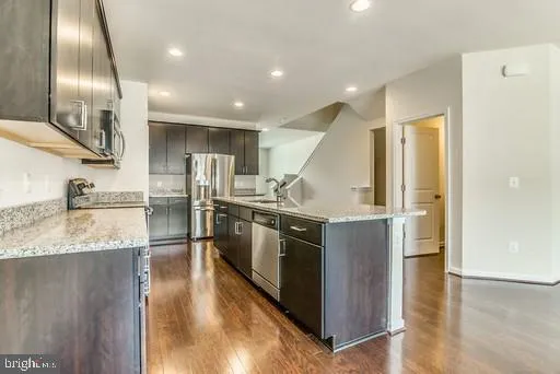 a kitchen with stainless steel appliances granite countertop a sink a stove and a refrigerator