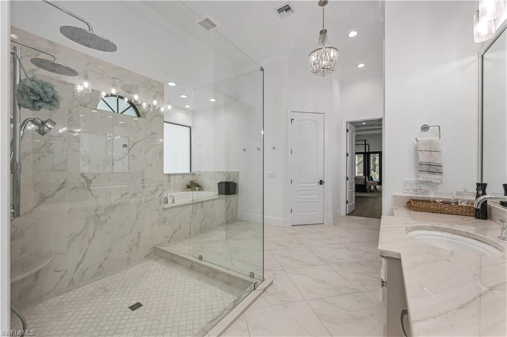 6689 Hunters Road Naples, FL 34109 - Photo 12 of 35 a bathroom with a granite countertop sink a mirror and shower