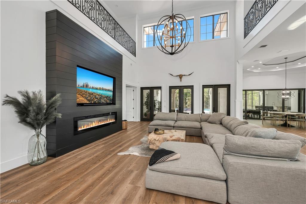 6689 Hunters Road Naples, FL 34109 - Photo 3 of 35 a living room with furniture a chandelier and a flat screen tv