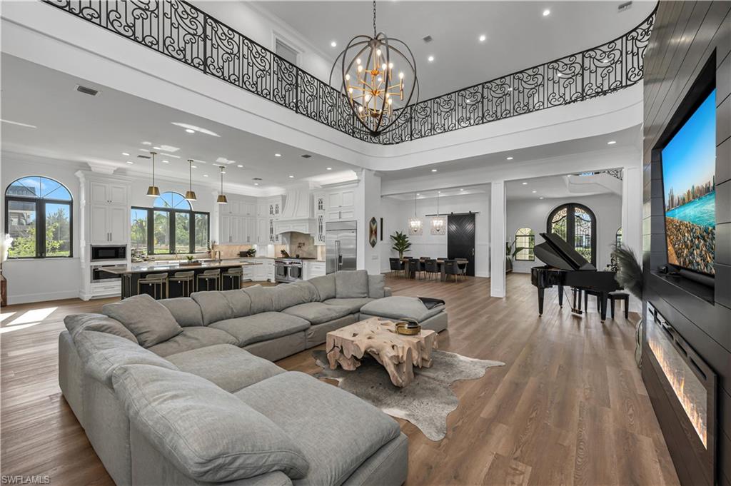 6689 Hunters Road Naples, FL 34109 - Photo 4 of 35 a living room with furniture a chandelier and a flat screen tv