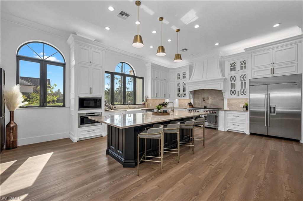6689 Hunters Road Naples, FL 34109 - Photo 5 of 35 a kitchen with stainless steel appliances granite countertop a kitchen island a stove a table and chairs