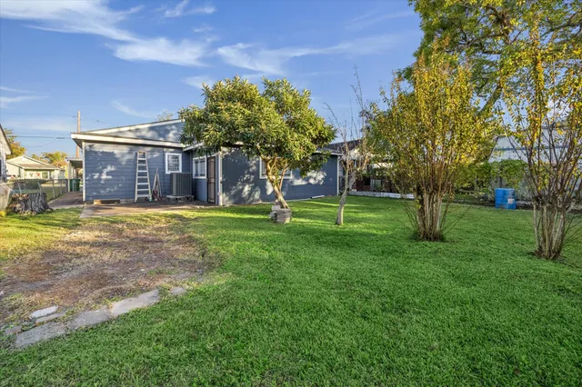 a view of a house with a big yard and large trees
