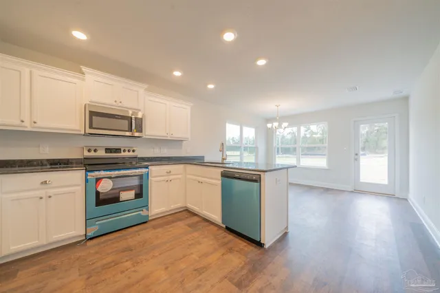 a kitchen with granite countertop a stove a sink and a microwave